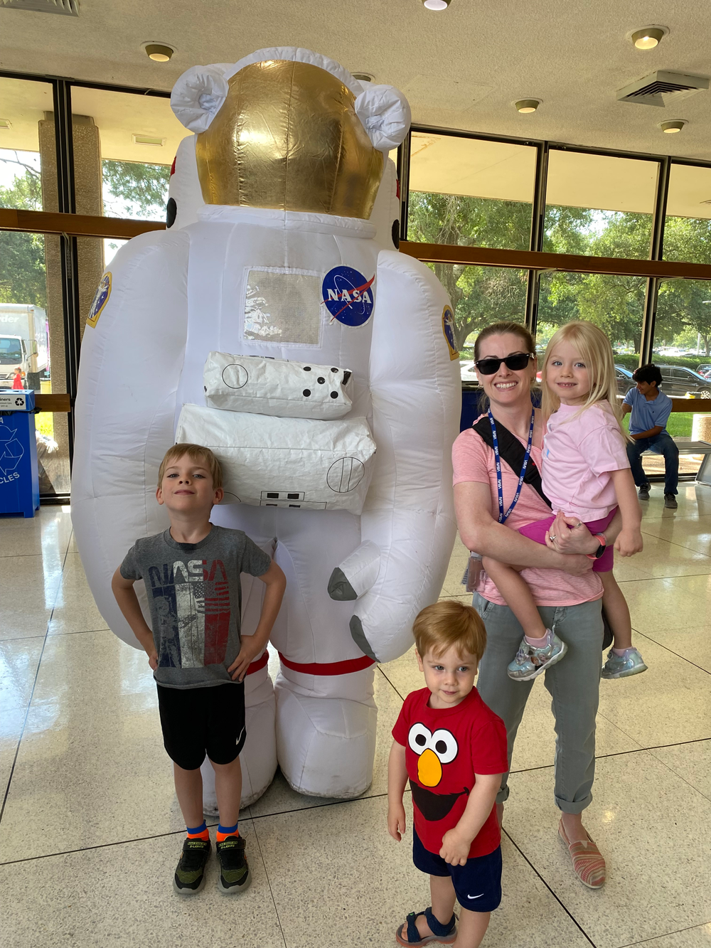 A woman and her three young kids pose with a large blow-up astronaut.